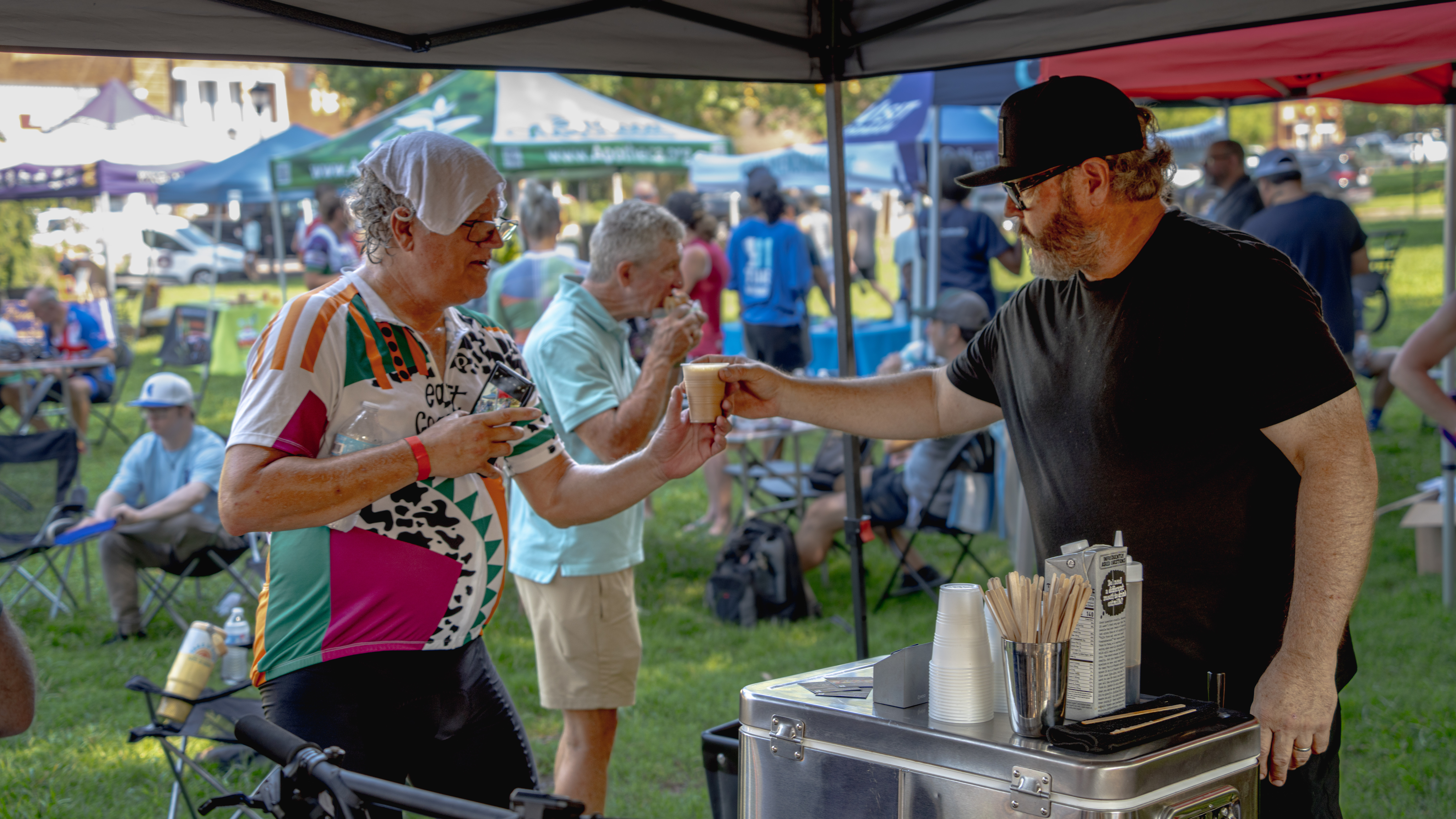 Sponsor tent at the Lake Norman Fondo finish line — vendors serving riders at Davidson Town Green