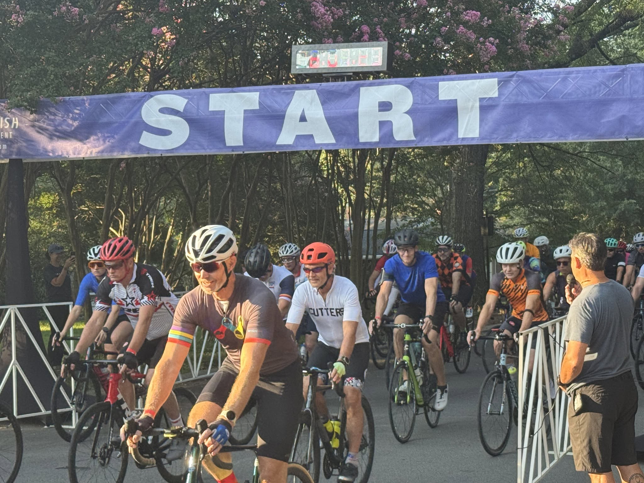 Riders rolling under the START arch at Davidson Town Green